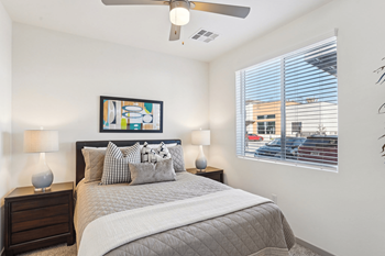 A bedroom with a bed, two lamps, and a painting on the wall.